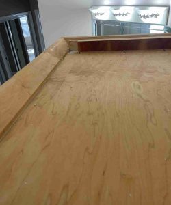 A close-up view of a wooden ledge with glass display cases and lights in the background.