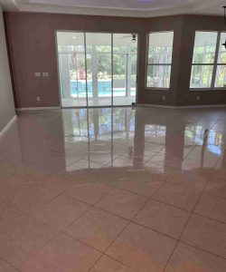 Spacious empty room with tiled floor, large windows, and glass doors opening to a patio and pool area outside.