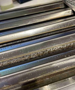 Close-up of metal baguette baking trays with some burnt residue and discoloration on the surface.